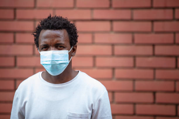 istock African-American young man with protective face mask looking at camera suspiciously 1262691943