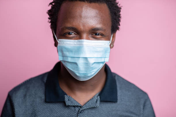 istock African-American young man smiling behind the protective face mask 1262691948