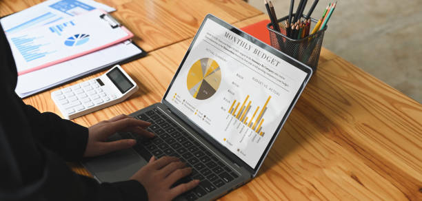 istock Cropped image of Businesspeople is using a computer laptop with graphic charts on screen at the wooden desk. 1262694342
