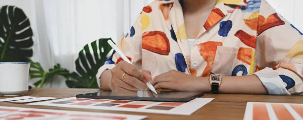 istock A graphic developer is using a computer tablet and stylus pen at the wooden working desk. 1262694376