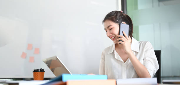 istock A businesswoman is talking on the mobile phone while sitting and using a computer laptop at the working desk. 1262694417