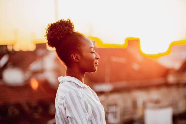 Young African American woman is relaxing on the rooftop Young African American woman is on the balcony at sunset mental wellbeing stock pictures, royalty-free photos & images