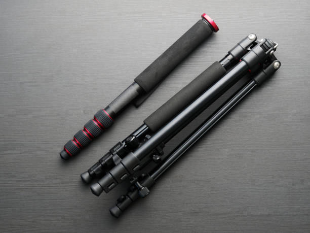 Black modern quality tripod and monopod together on a dark table.