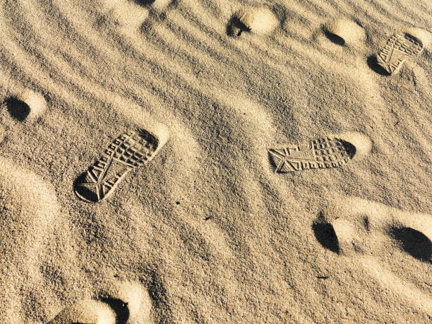 Personal perspective of sneakers and sand during the day