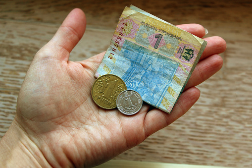 Paper and metal money in the size of one hryvnia on a woman's hand.