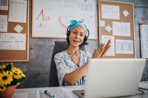 Female professor holding online class and clapping hands to students for good answers One young female professor holding online class for e-learning students during coronavirus pandemic period. online tutors stock pictures, royalty-free photos & images