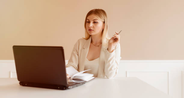 istock Young woman in the home office sitting at the table using laptop computer 1262735140