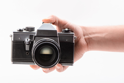 Hand holding a retro-style camera on white background. Digital photography equipment.