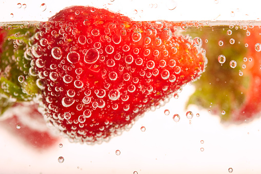 Strawberry submerged into a container of soda water.