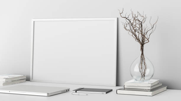 istock Horizontal poster frame mockup on the white table of home studio workspace with white wall. Side view, clipping path around poster picture. 1262749449