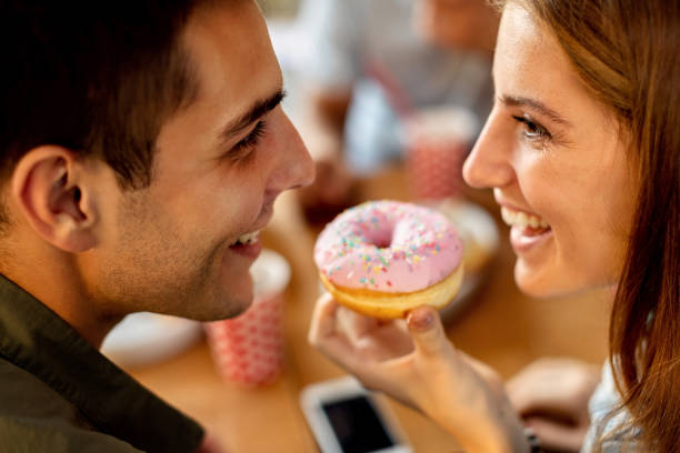 istock Close-up of happy couple sharing a doughnut. 1262749761