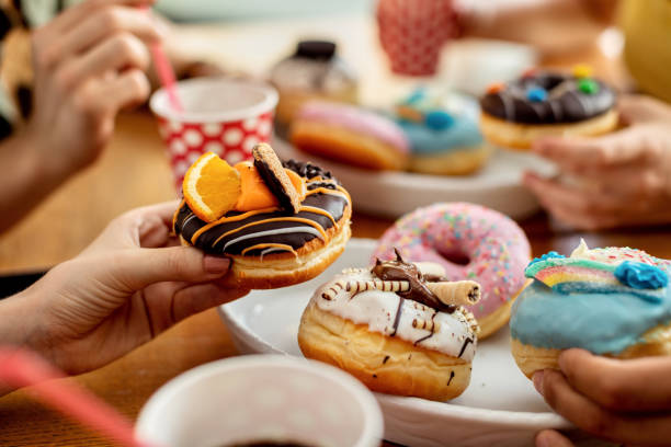 istock Close-up of friends eating donuts. 1262749767