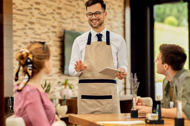 istock Happy waiter taking order from guests in a cafe. 1262751498