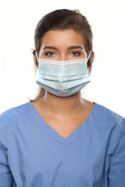 Young Woman Wearing Medical Scrubs and a Surgical Mask vertical photograph of a Young Woman Wearing Medical Scrubs and a Surgical Mask 1528 stock pictures, royalty-free photos & images