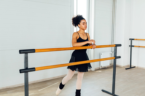 Woman in dancewear standing at ballet barre during training