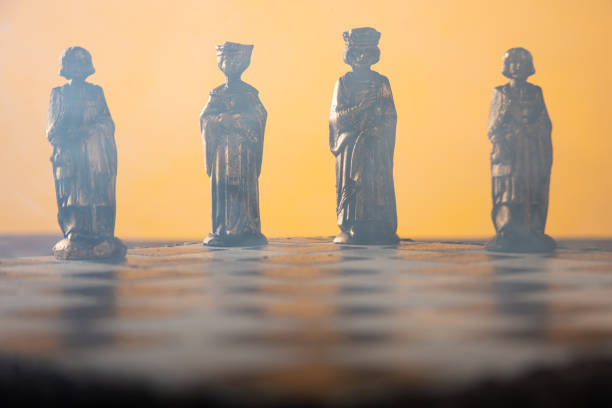 istock stylized chess pieces on a board with orange background, smoke and selective focus 1262755400