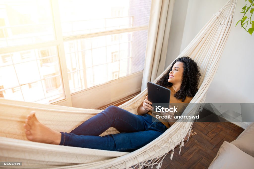 woman relaxing and using tablet relaxing woman swinging on hammock using tablet Hammock Stock Photo