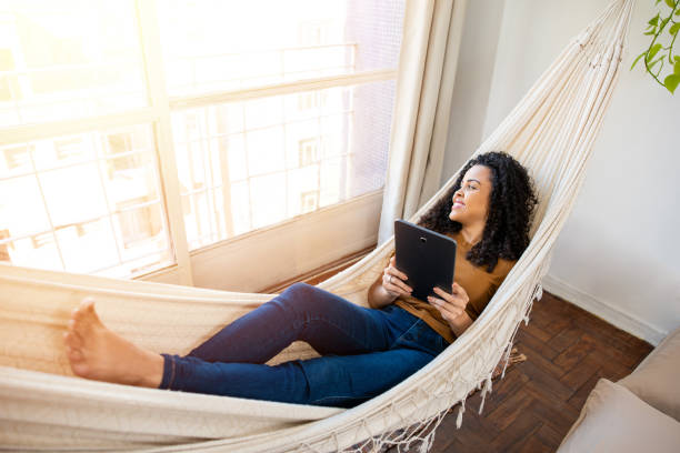 woman relaxing and using tablet relaxing woman swinging on hammock using tablet hammock stock pictures, royalty-free photos & images