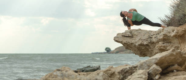 istock Young woman practicing yoga on a rocky seaside 1262759219
