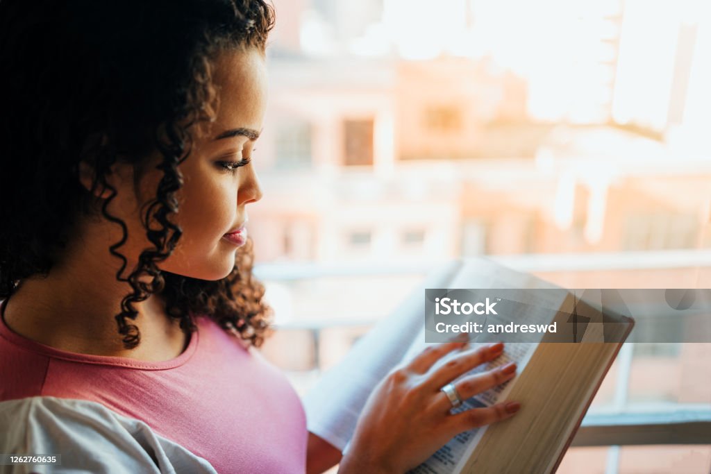 Woman reading the bible Woman reading the bible beside the window with natural light Bible Stock Photo