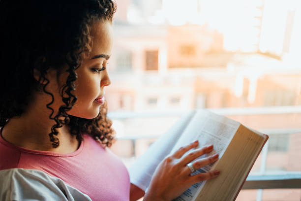 woman reading the bible - bible holding reading book imagens e fotografias de stock