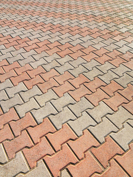istock Decorative colorful sidewalk pavement. Tiled floor with grey tiles crossed by a diagonal double stripe of red tiles viewed at a low angle, full frame background pattern 1262763524