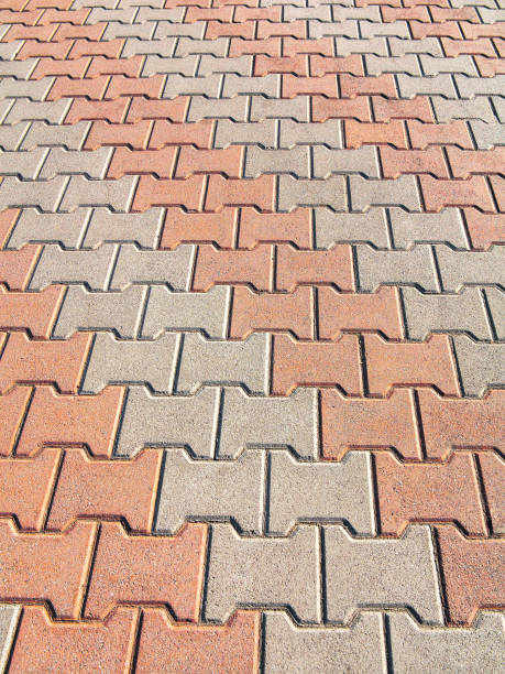 istock Decorative colorful sidewalk pavement. Tiled floor with grey tiles crossed by a diagonal double stripe of red tiles viewed at a low angle, full frame background pattern 1262763526