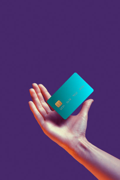 nahaufnahme weibliche hand hält schwebende vorlage mockup bank kreditkarte mit online-service isoliert auf violetten hintergrund - bankkarte stock-fotos und bilder