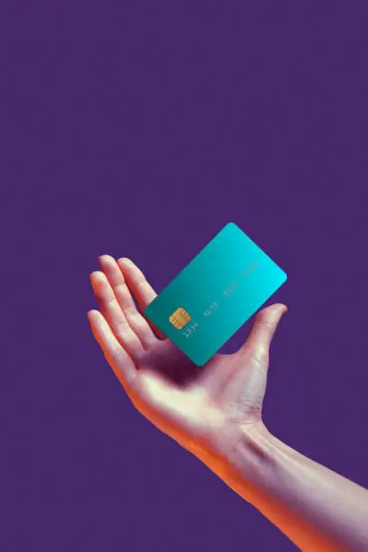 Close up female hand holds levitating template mockup Bank credit card with online service isolated on violet background. High quality photo