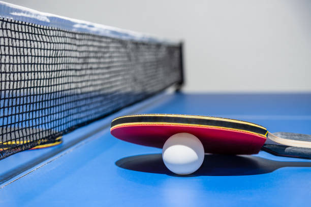 istock Closeup red table tennis paddle white ball and a net 1262768799
