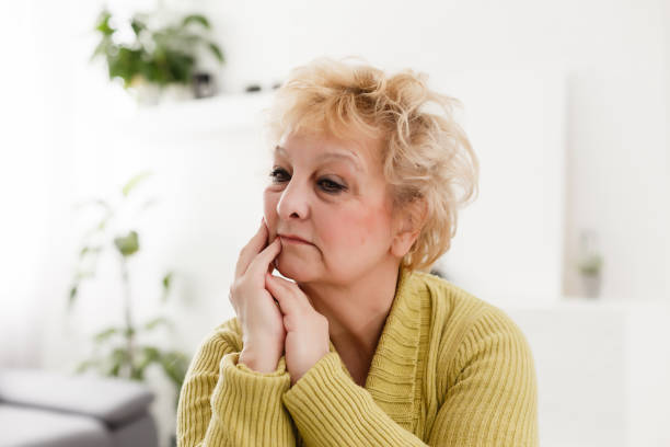 istock Attractive elderly woman sitting on couch at home, looking at camera, makes video call, communication distantly, modern wireless technologies concept 1262776747