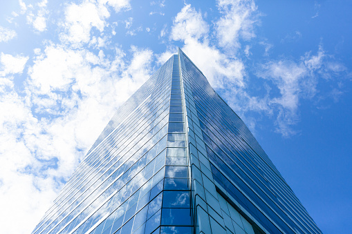 Low angle view of modern office building with clouds reflection, skyscrapers, sky background with copy space, full frame horizontal composition