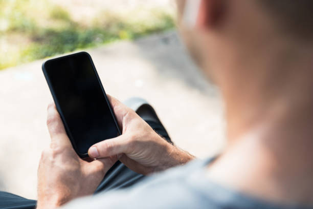 istock Unrecognizable man sits outside and enjoys his smart phone 1262786704