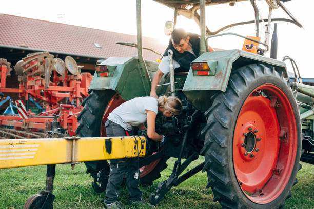 profession agricole: deux agriculteurs réparent une remorque sur un tracteur - vehicle trailer flash photos et images de collection