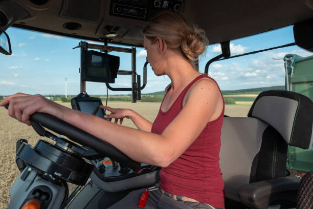 istock while harvesting a female farmer drives the tractor over the wheat field 1262790802