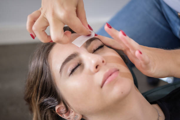 femme recevant le traitement de cire de sourcil au salon de beauté - épilation à la cire photos et images de collection