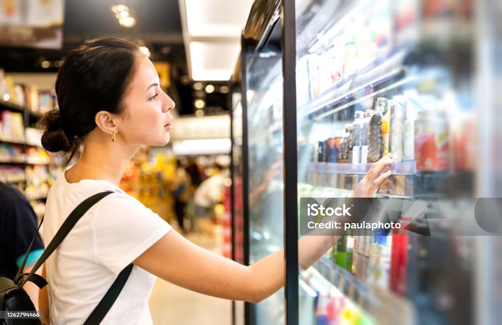 Portrait of caucasian woman looking at product at grocery store. Happy hispanic girl shopping in supermarket reading product information. Costumer buying food at the market, woman lifestyle concept. Supermarket Stock Photo