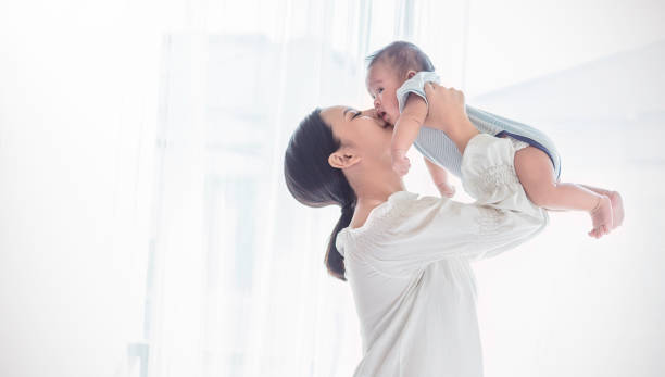 portrait of asian mother lifting and playing with newborn baby, baby talking to mother. health care family love together. asian girl lifestyle. asia mother's day concept - mulher bebé imagens e fotografias de stock