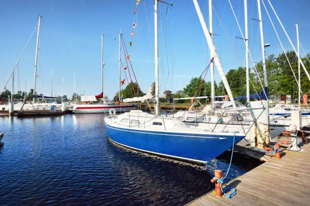 Photo of Elegant and modern sailing boats moored to a pier in a yacht marina at sunset.