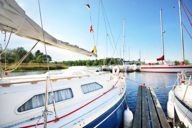 Photo of Elegant and modern sailing boats moored to a pier in a yacht marina at sunset.