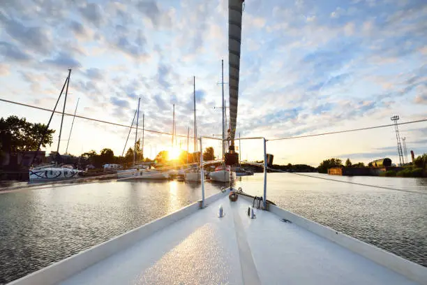 Photo of Elegant and modern sailing boats moored to a pier in a yacht marina at sunset.