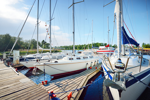 Elegant and modern sailing boats (for rent) moored to a pier in a yacht marina at sunset. Transportation, cruise, leisure activity, sport and recreation theme. Sweden