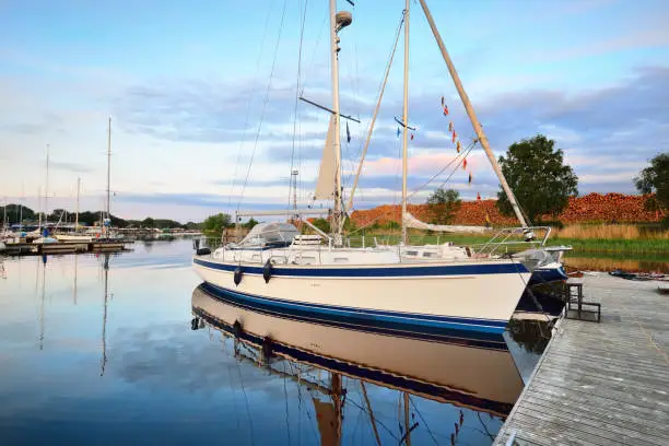 Photo of Elegant and modern sailing boats moored to a pier in a yacht marina at sunset.