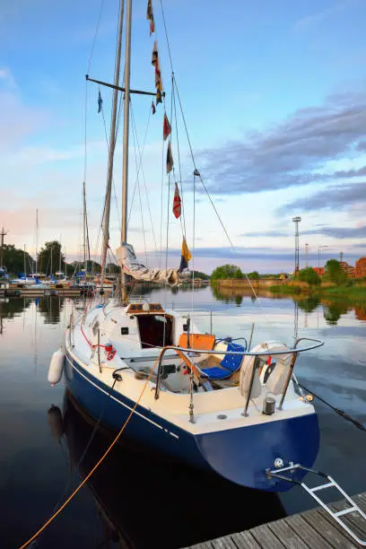 Photo of Elegant and modern sailing boats moored to a pier in a yacht marina at sunset.