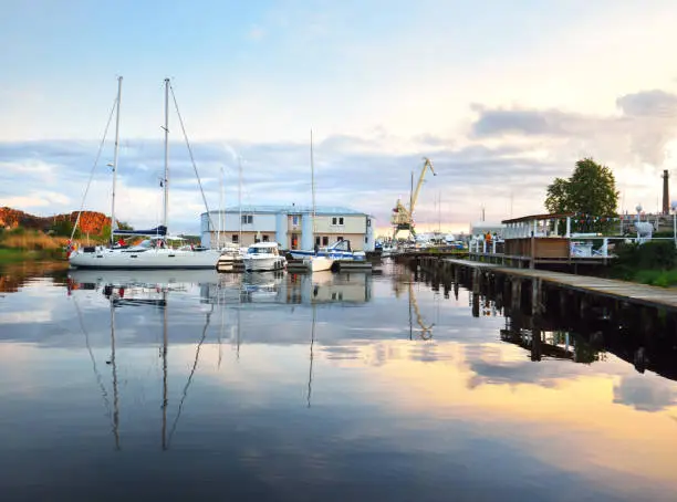 Photo of Elegant and modern sailing boats moored to a pier in a yacht marina at sunset.