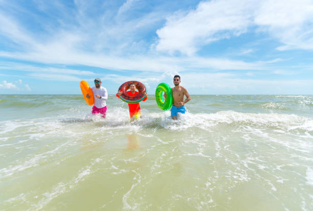 istock Hispanic guys with inflatable ring tubes on the beach 1262801994