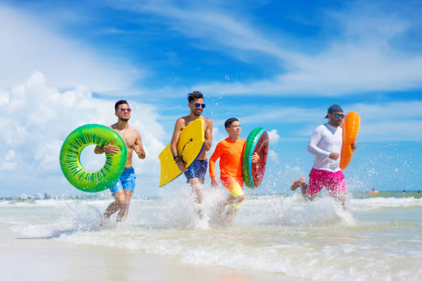 istock Four guys with inflatable ring tubes on a beach in Florida 1262802494