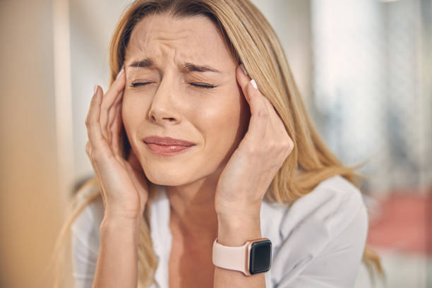 istock Unhappy young woman touching temples while having headache 1262805368