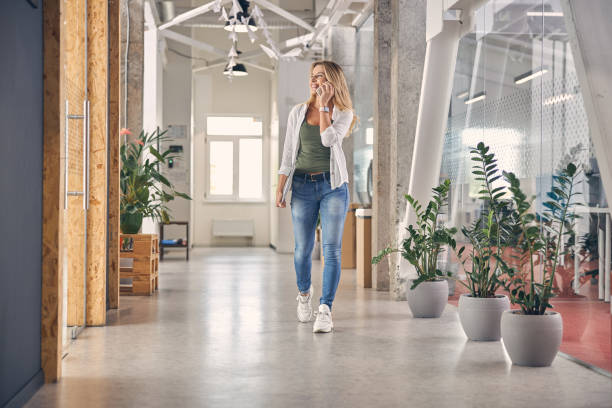 Cheerful young woman talking on cellphone in office