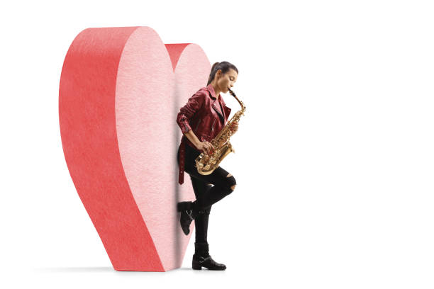 istock Young woman playing a saxophone and leaning on a red heart 1262822672